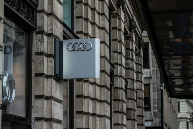 Detailed exterior of a modern building with a prominent Audi logo in an urban setting.